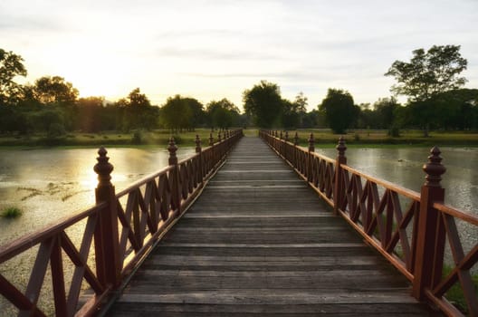 wooden bridge across the lake in the evening