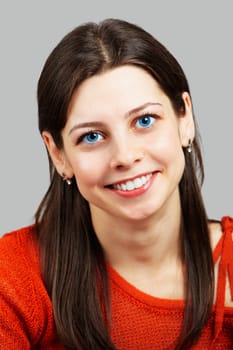 Portrait of a beautiful young woman smiling with red top over grey.
