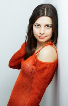 Portrait of a beautiful young woman with red top leaning against a wall.