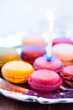 Closeup of macaroons with candle on decorative silver tray