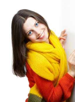 Portrait of a beautiful young woman with yellow scarf and red top leaning against a white wall.