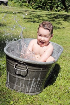 joy caucasian child bathing outdoors in bath with water drops