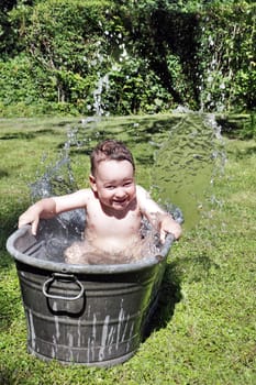 joy caucasian child bathing outdoors in bath with water drops