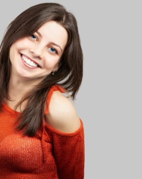 Portrait of a beautiful young woman with red top smiling over grey background.