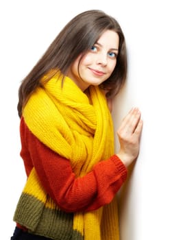 Portrait of a beautiful young woman with yellow scarf leaning against a white wall.
