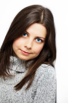 Portrait of a beautiful young woman leaning against a white wall.