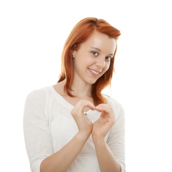 young beautiful red haired girl forming a heart of her hands in front of white background