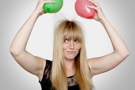 young beautiful blond haired girl with electric loaded balloons in front of grey background