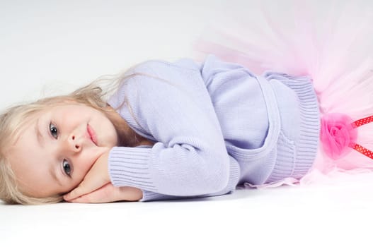 Studio shot of ballet dancer girl lying on the floor