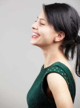 Portrait of a beautiful young woman wearing a green elegant dress over grey background.