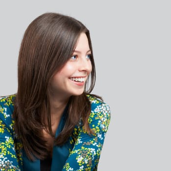 Portrait of a cheerful young woman over grey background.