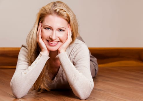 pretty blond woman wearing beige top relaxing on the floor