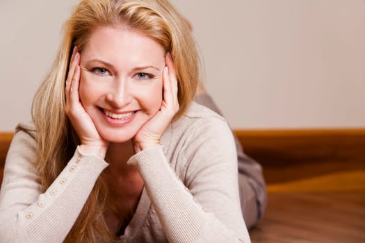 pretty blond woman wearing beige top relaxing on the floor