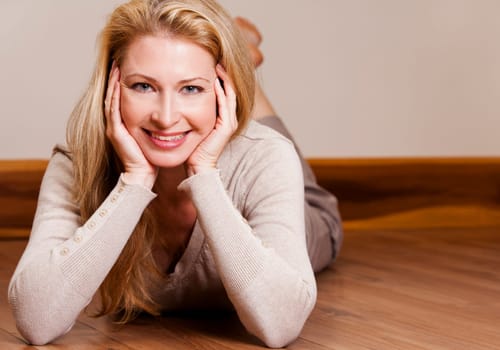 pretty blond woman wearing beige top relaxing on the floor