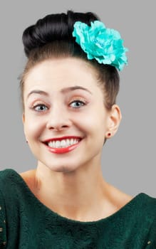 Portrait of a beautiful young woman with a flower in her hair isolated on grey