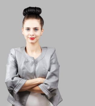 Portrait of a beautiful young woman with grey jacket over grey background.