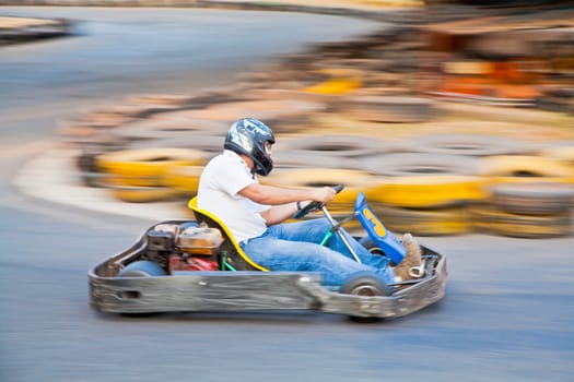 Horizontal take of an Asian driver and go kart as they zoom past on a public race track in Goa India