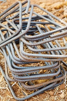Vertical capture of wrought iron rods used in the construction industry as concreteing ties. Generic shot taken in Maharashtra, India of the rectangular shapes laid on a dry grass ground