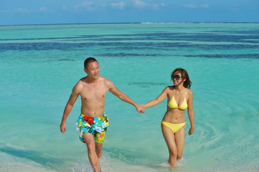 happy young asian couple enjoying summer and have on beautiful white sand beach