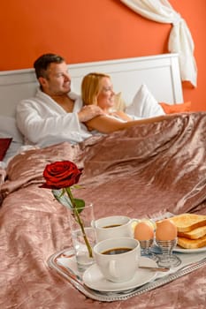 Romantic breakfast hotel room service young couple watching bed
