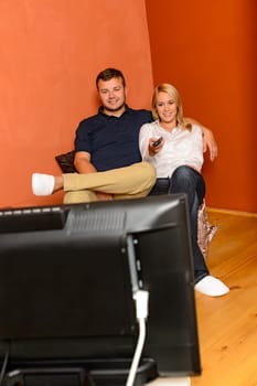 Smiling couple changing channels watching television evening using remote control