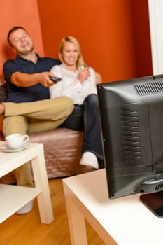 Laughing couple watching television together relaxing living room