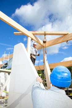 construction workers at work with wooden  roof construction of a new home