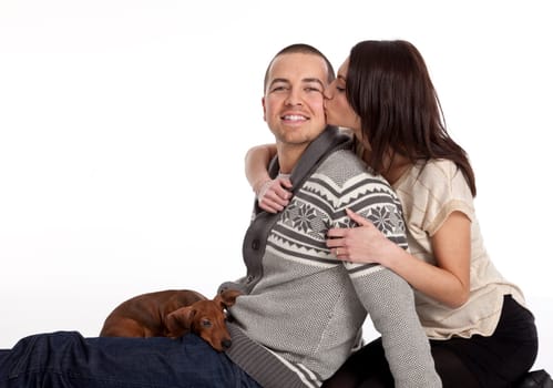 Young adult couple kissing on the cheek on white background