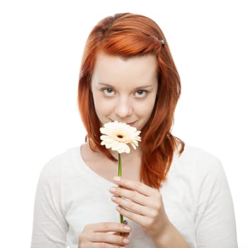 young beautiful red haired girl smelling on a flower in front of white background