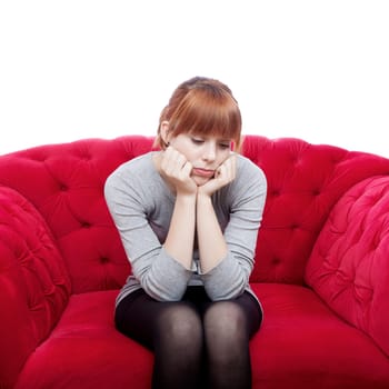 young beautiful red haired girl sit alone on red sofa in front of white background