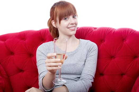 young beautiful red haired girl on red sofa cheers with you in front of white background