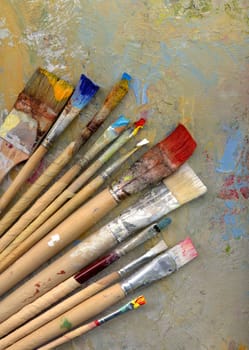 Different brushes with paint on painted background