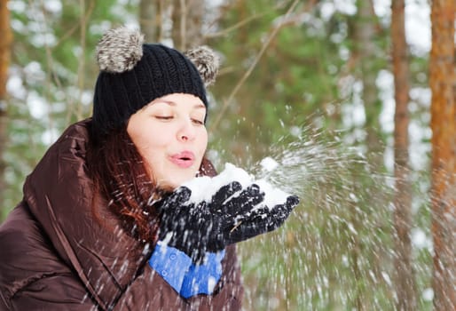 Cute young woman playing with snow  outdoors
