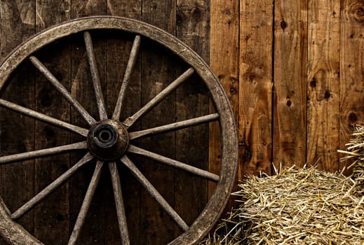 Vintage wooden carriage wheel, straw and wood background