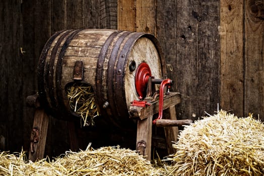 Vintage barrel-type butter churn filled with straw, wooden background