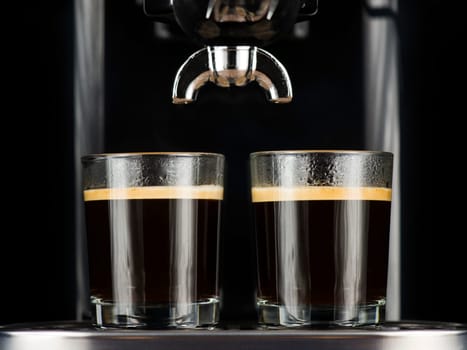 Two espresso cafes served in glasses under the percolator