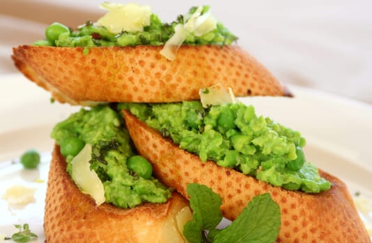 Delicious green pea baguettes with shaved cheese and mint with avocado oil.