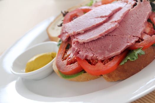Delicious corn beef open sandwich with mustard and fresh garden salad.