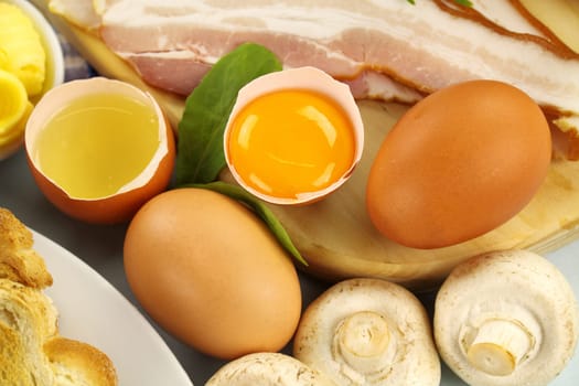 Omelette ingredients cosisting of eggs mushrooms bacon and butter.