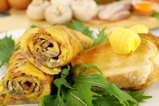 Delicious rolled mushroom and bacon omelette with butter and toast with ingredients.