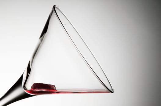 Studio shot of a martini glass tilted 45 degrees with red liquid against a white-gray background