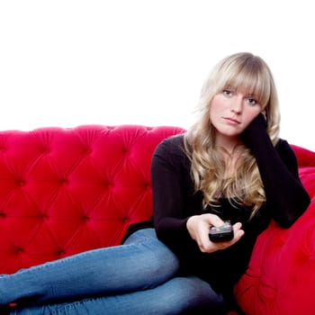 young blond haired girl on red sofa with remote control in front of white background