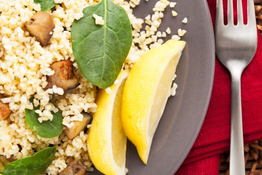Bulgur salad with spinach roasted eggplant and a lemon wedge
