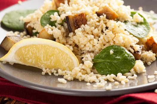 Bulgur salad with spinach roasted eggplant and a lemon wedge
