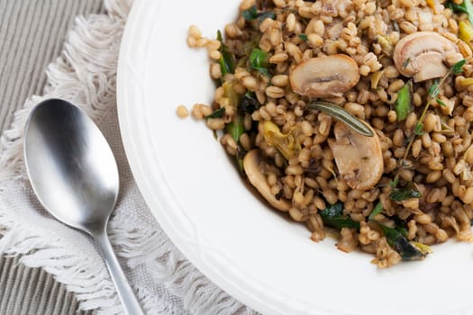 Healthy vegan barley dish with mushrooms collard greens, thyme and rosemary.