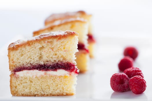 Victoria sponge cake with cream and jam filling, served with raspberries