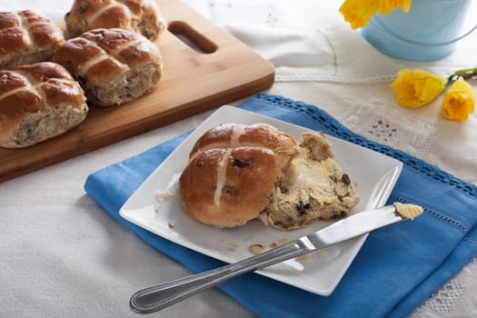 Hot cross bun with butter and butter knife