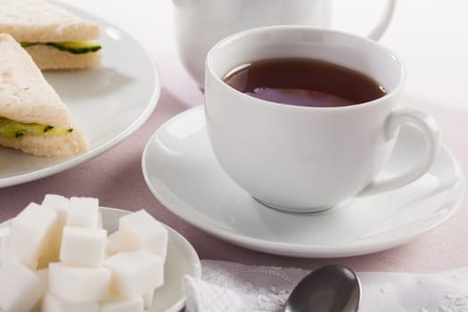 Cup of tea with sugar cubes and other afternoon tea treats