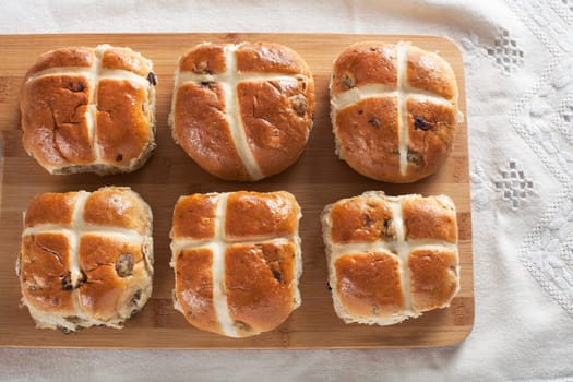 Six hot cross buns on a wooden cutting board