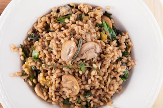 Healthy vegan barley dish with mushrooms collard greens, thyme and rosemary.